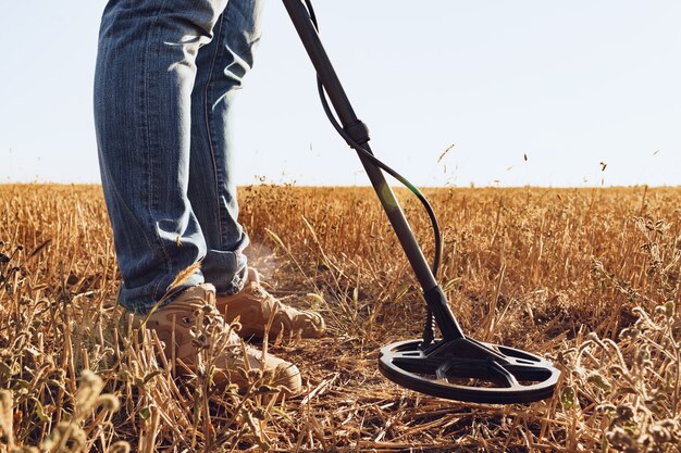 Man with metal detector equipment searching for metal goods in the field