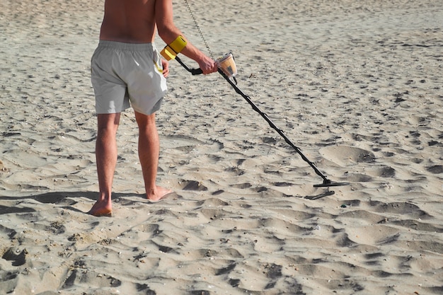 Man with a metal detector on a sea sandy beach in summer day