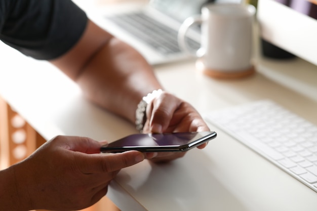 Man with mobile smart phone on working desk