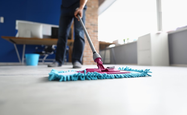 Man with mop washes floor in office closeup