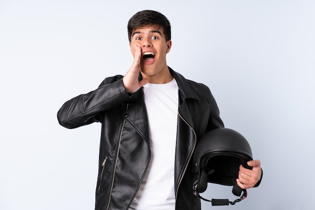 Man with a motorcycle helmet over blue wall shouting with mouth wide open