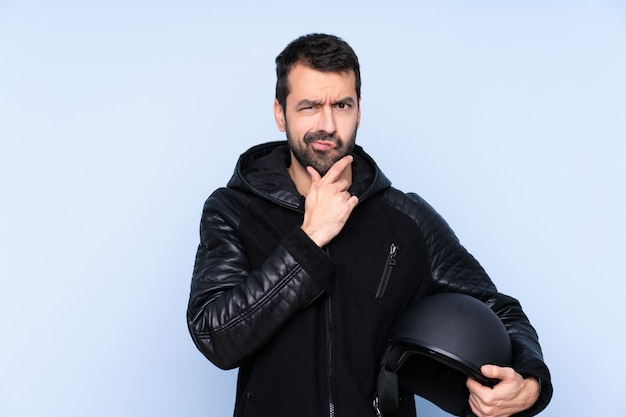 Man with a motorcycle helmet over isolated wall thinking