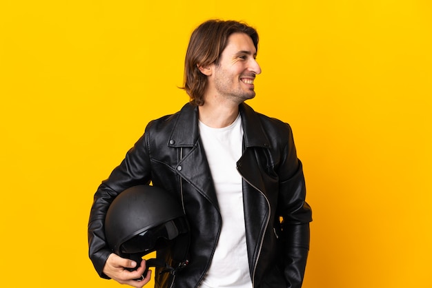 Man with a motorcycle helmet isolated on yellow looking side