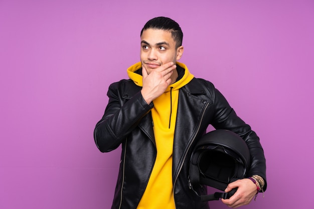 Man with a motorcycle helmet on purple wall thinking an idea