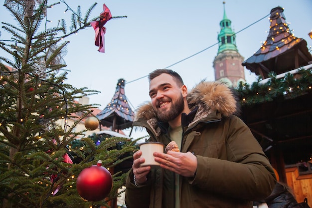 Man with mug of drink and trdelnik on Christmas market in Wroclaw, Poland