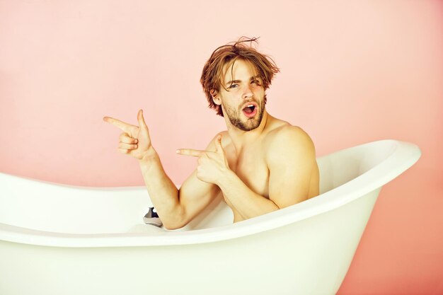 Man with muscular body sitting in white bathtub