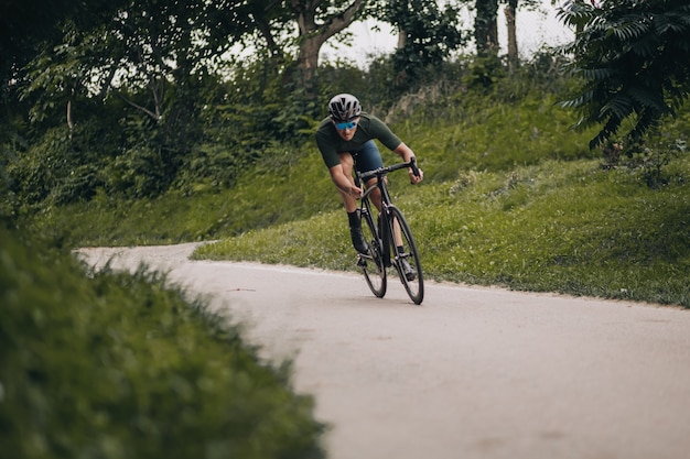 Man with muscular cycling alone at green city park