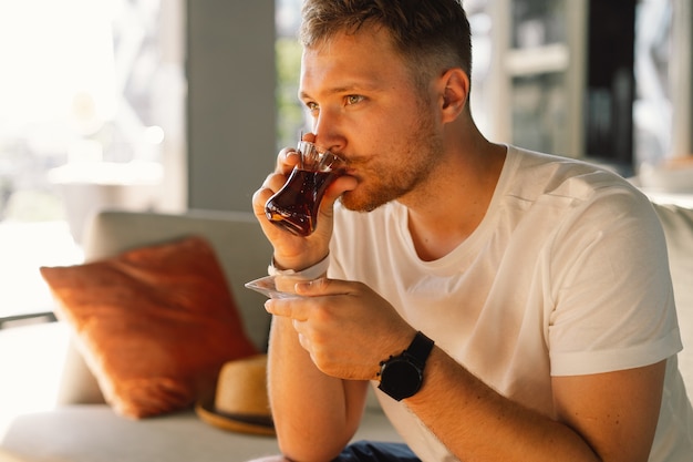 A man with mustache drinks and enjoy turkish traditional hot tea in the lobby of a turkish hotel