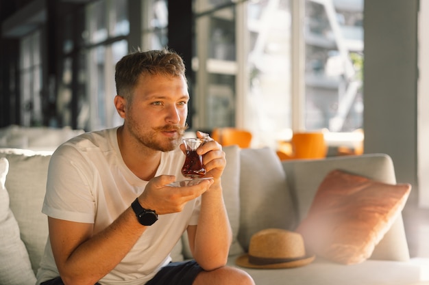 A man with mustache drinks and enjoy turkish traditional hot tea in the lobby of a turkish hotel