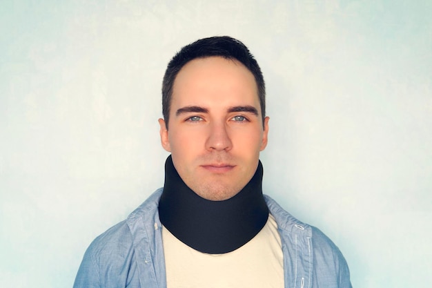 Man with neck brace after whiplash injury blue background black neck collar on male patient treatment of diseases of neck and blood vessels of the brain