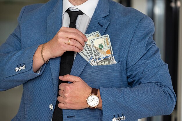 A man with a noble physique in a white shirt and tie shows a large sum of dollars in himself