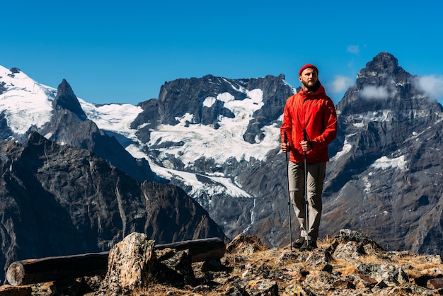 山にノルディックウォーキングの棒を持った男。コーカサスを旅する男。マウンテンスポーツ。マウンテンツーリズム。徒歩旅行。山への旅。山々の間を歩くノルディックウォーキング。