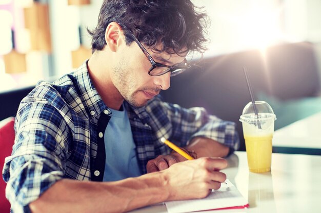 Foto uomo con quaderno e succo che scrive al caffè