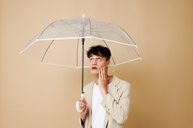 A man with an open umbrella in a jacket protection from the rain beige background