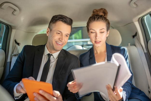 Man with orange tablet, woman with papers