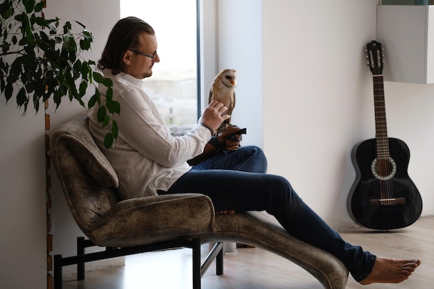 Photo man with owl at home bird pet in hands