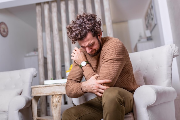 Photo man with pain in elbow. pain relief concept. handsome young man feeling the pain in hand elbow at home . businessman's elbow pain, a young man touching her painful elbow