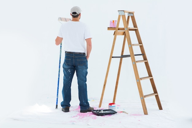 Man with paint roller standing by ladder