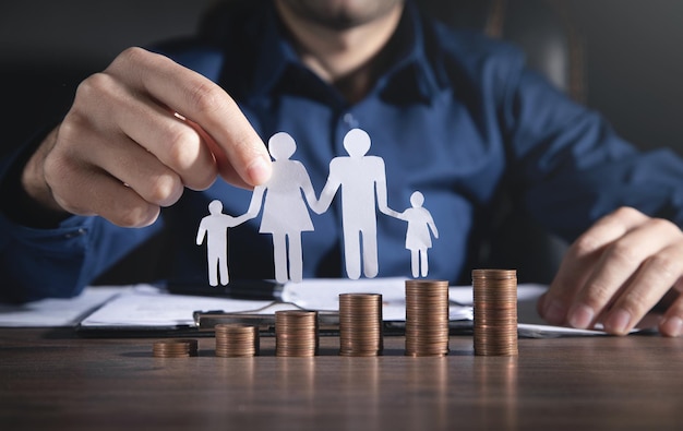 Man with a paper family and stack of coins.