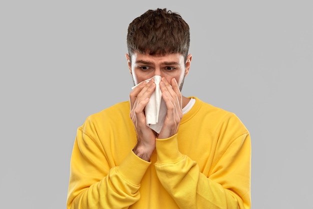 man with paper napkin blowing nose