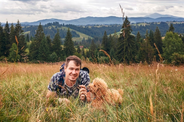 Man with a poodle dog on a background of mountain landscape