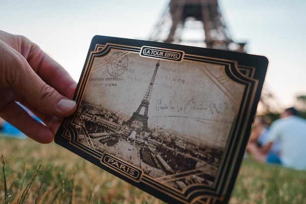 Foto uomo con una cartolina davanti alla torre eiffel