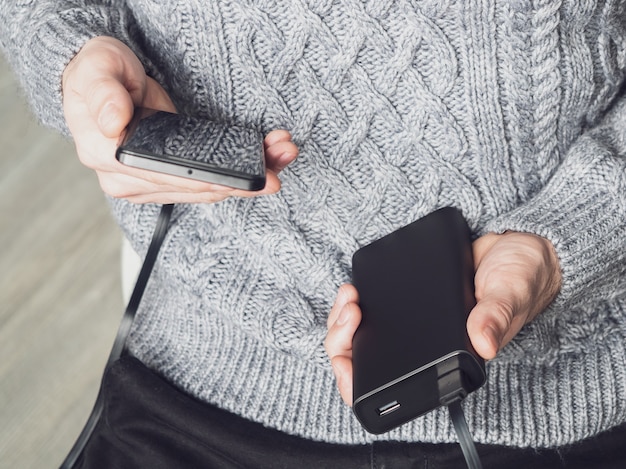 Фото Человек с power bank заряжает телефон через кабель