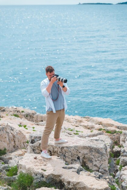 海岸の写真を撮るプロのデジタル一眼レフカメラを持つ男