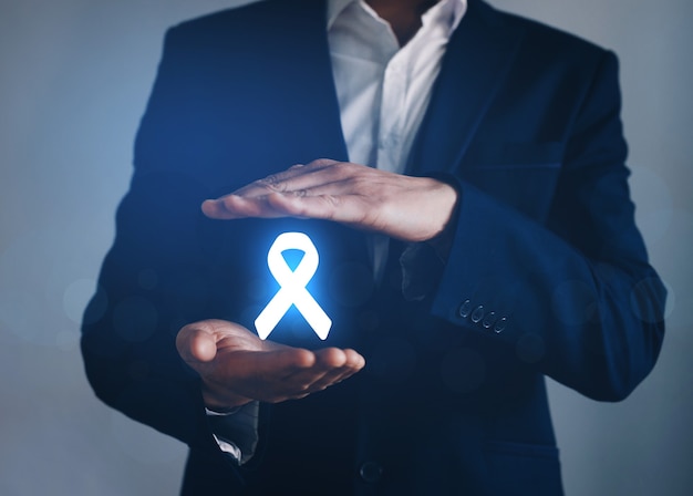 Man with protective hand holding   digital ribbon for supporting people living and illness. World cancer day concept.