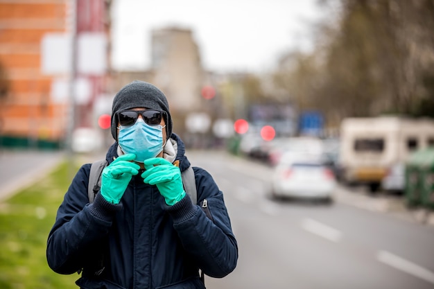 Photo man with a protective mask on his face is standing on the street