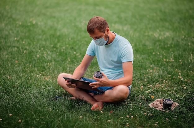 Man with a protective mask using a laptop in nature