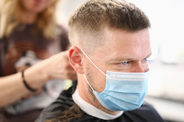 Man with protective medical mask at hairdresser salon