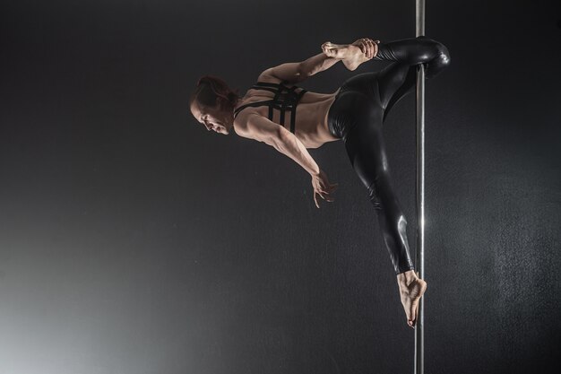 Man with pylon, Male pole dancer dancing on a black background