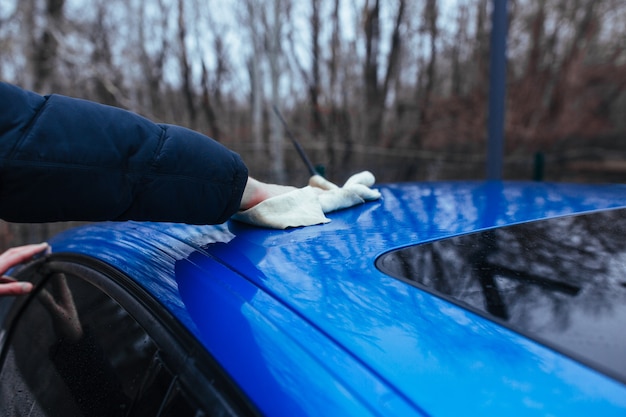 Un uomo con uno straccio per asciugare l'auto. concetto di autolavaggio