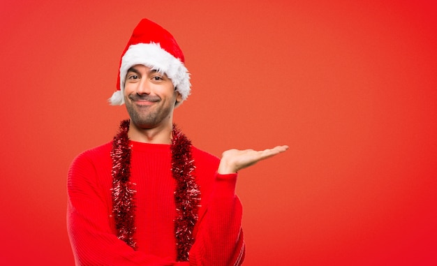 Man with red clothes celebrating the Christmas holidays holding copyspace imaginary on the