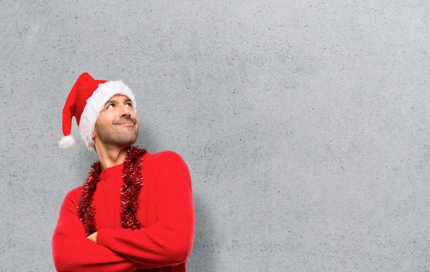 Человек с красной одежды празднует рождественские праздники, глядя вверх, улыбаясь