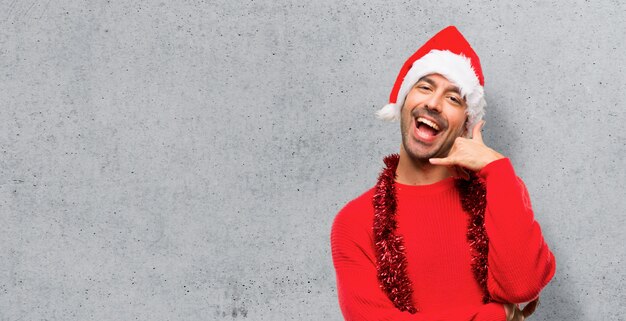 Man with red clothes celebrating the Christmas holidays making phone gesture. 