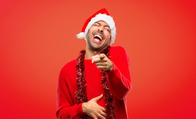 Man with red clothes celebrating the Christmas holidays pointing with finger at someone