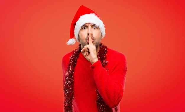 Man with red clothes celebrating the Christmas holidays showing a sign of silence gesture 