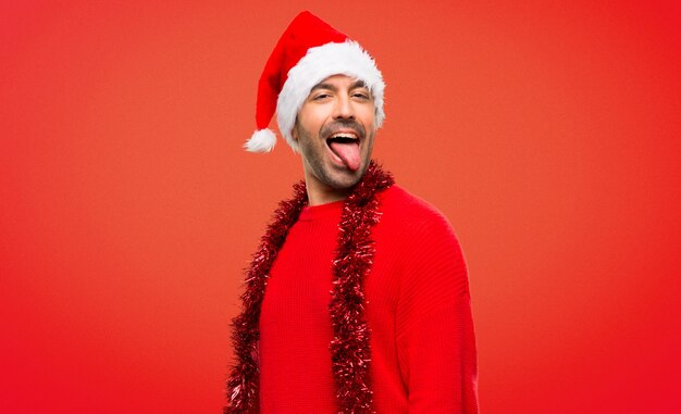 Man with red clothes celebrating the Christmas holidays showing tongue at the camera