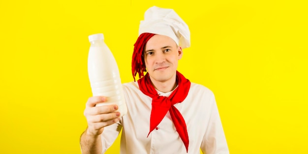 Man with red dreadlocks with bottle milk Confident young cook in white shirt and red tie holding bottle of milkr and looking at camera while