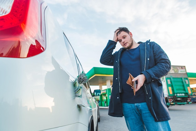 Photo man with sad view and empty wallet at gas station dollars money