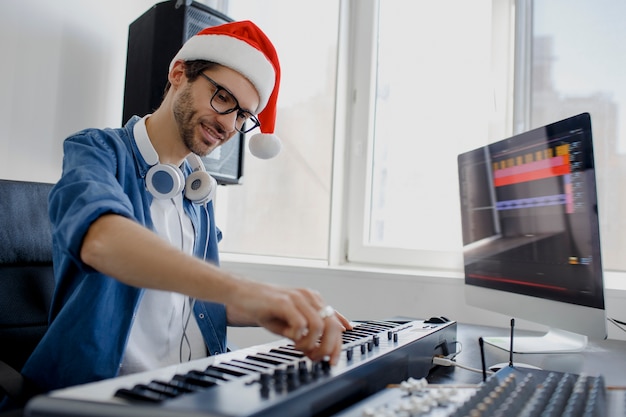 Uomo con cappello santa suonare il pianoforte in studio