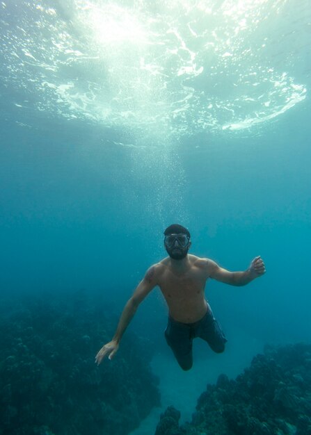 Uomo con attrezzatura subacquea nuotare nell'oceano