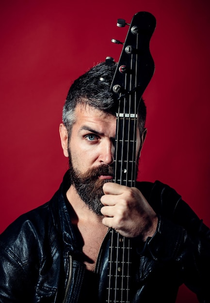 Man with serious face in black clothes holds guitar musician\
artist play electric guitar musical