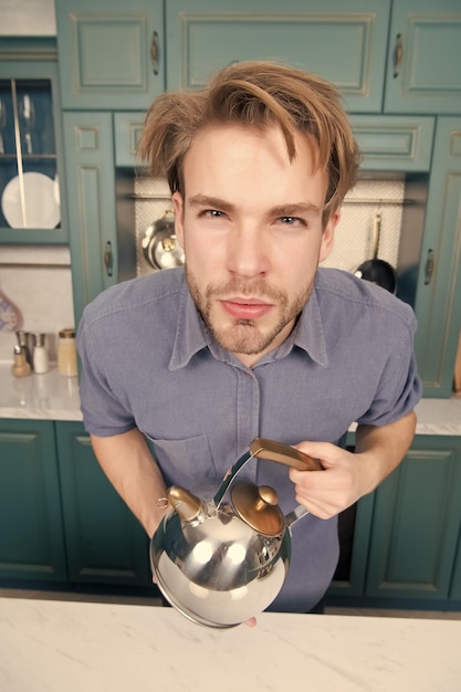 Man with serious face in blue shirt hold kettle