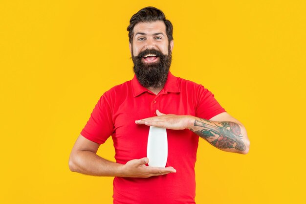 Man with shampoo cosmetics on background photo of man smile with shampoo cosmetics man with shampoo cosmetics isolated on yellow man with shampoo cosmetics in studio