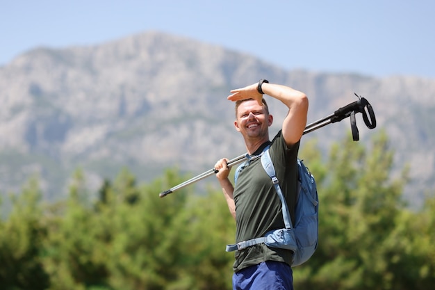 Man with shelves for hike in his hands looking into distance in mountains. Outdoor activities hiking concept