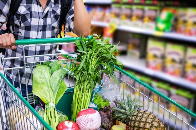 Foto uomo con carrello acquisti alimentari in un supermercato. particolare del primo piano del carrello.