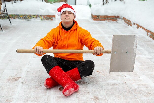 Un uomo con una pala per pulire la neve pronto a combattere la neve pulito il territorio siede nel loto